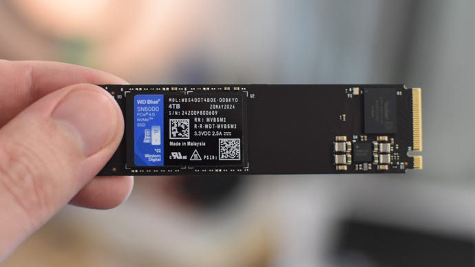 The WD Blue SN5000 SSD, held between fingers.